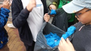 Trzej chłopcy wrzucają śmieci do worka