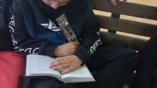 Chłopiec siedzi na krześle i czyta książkę