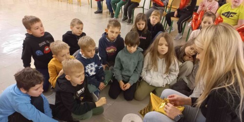 Pani siedząc przed uczniami pokazuje jak pracować z balonem