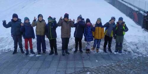 Uczniowie stoją na tle Centrum Spotkania Kultur w zimowej scenerii