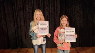 Dwie uczennice nagrodzone w konkursie szczodraki stoją na scenie z dyplomami
