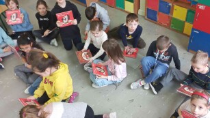 Dzieci przeglądają pozycje książkowe. Siedzą w klasie i oglądają książki
