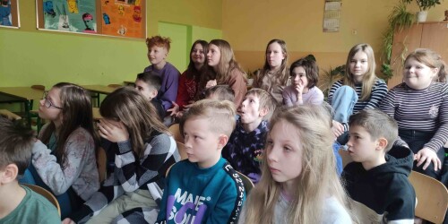 Uczniowie klasy 4b podczas zdalnego spotkania siedzą oglądając swoich rówieśników z Gdańska