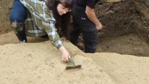 Dwójka studentów odsłania kolejne warstwy powierzchni podczas prac archeologicznych