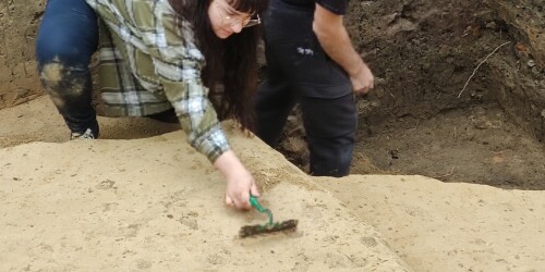 Dwójka studentów odsłania kolejne warstwy powierzchni podczas prac archeologicznych