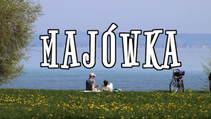Miniatura z napisaem majówka i dwojgiem ludzi siedzących nad brzegiem jeziora