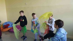 Chłopcy bawia się kolorowymi chustami. Żonglują nimi we wskazany przez instruktora schemat