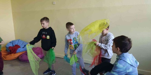 Chłopcy bawia się kolorowymi chustami. Żonglują nimi we wskazany przez instruktora schemat