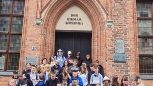 Zdjęcie grupowe klas 6a i 8b na tle wejścia do Domu Mikołaja Kopernika